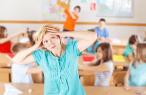 Frazzled teachers stands in front of classroom of out of control students